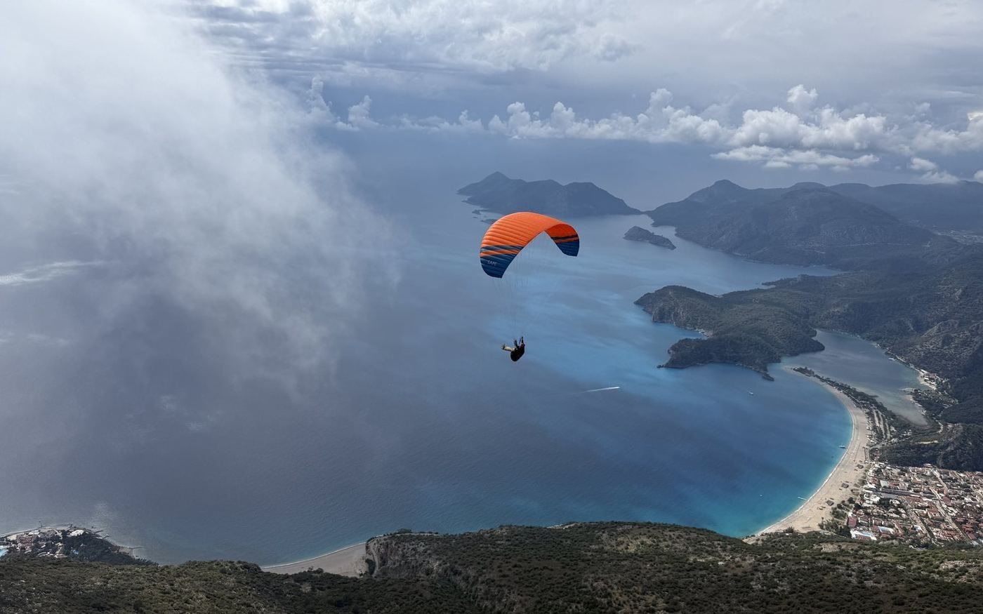 The Ölüdeniz bay seen between clouds with a wing in flight