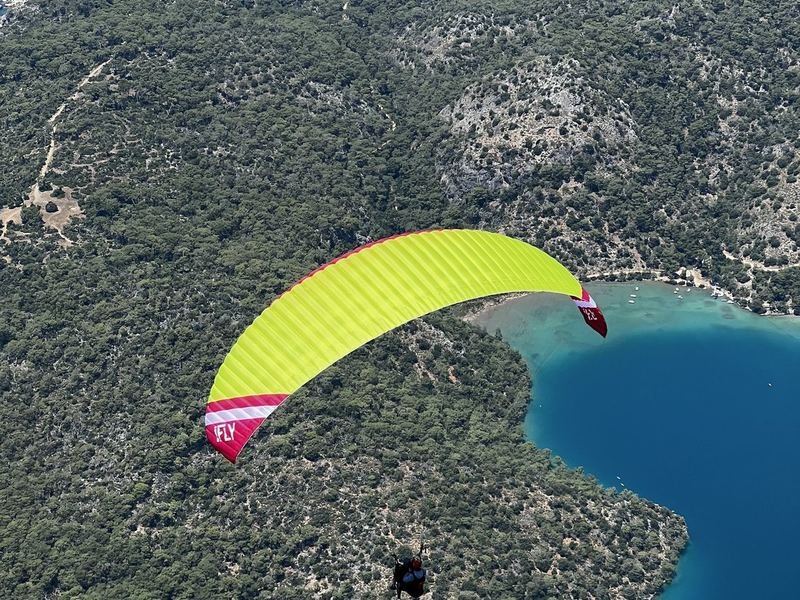 A paraglider flying along the coastline