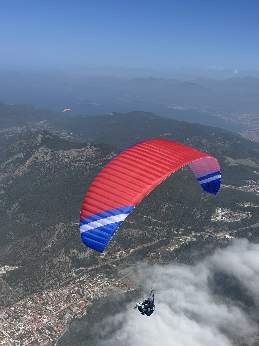 A paraglider flying above the clouds